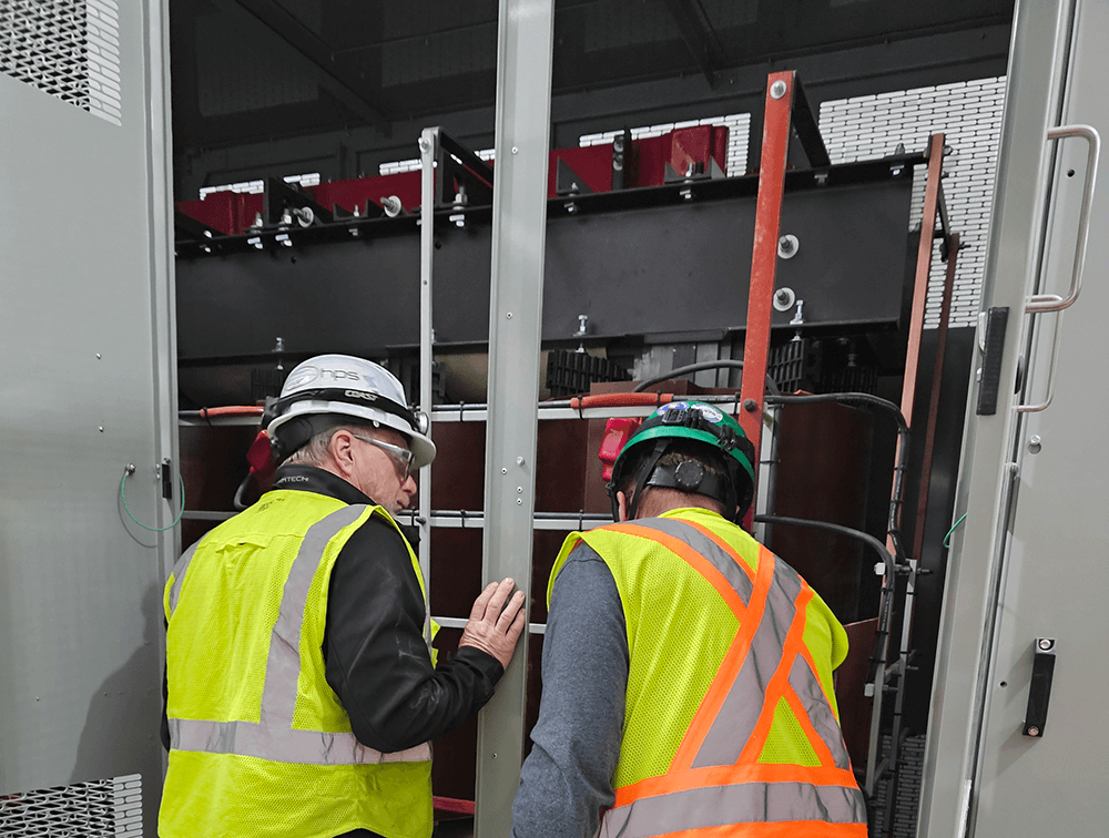 two service agents inspect transformer
